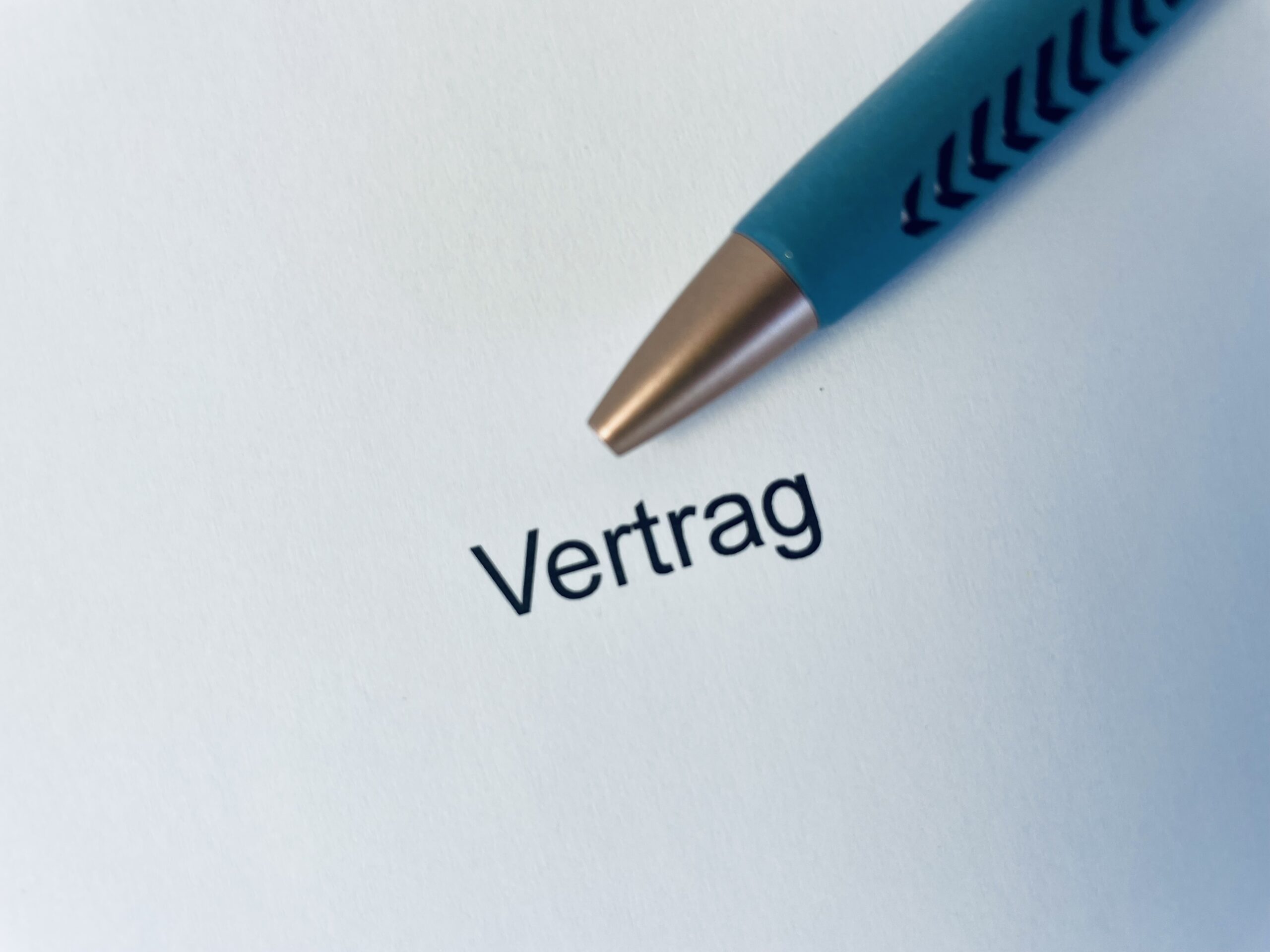 Das Bild zeigt einen Stift und ein Blatt Papier mit dem Wort „Vertrag“. Es soll zeigen, dass die Leistungen, die erbracht werden, in einem Vertrag festgehalten werden. So ist alles klar und geregelt. Das Bild zeigt einen Stift und ein Blatt Papier mit dem Wort „Vertrag“. Es soll zeigen, dass die Leistungen, die erbracht werden, in einem Vertrag festgehalten werden. So ist alles klar und geregelt.