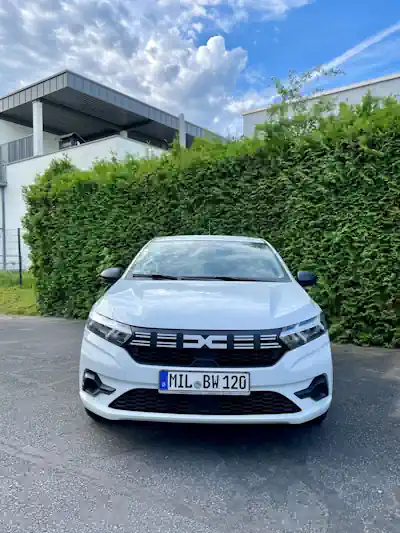 Dacia_Dienstfahrzeug Ein weißes Fahrzeug der Marke Dacia auf dem Hof bei Mitten im Leben. Im Hintergrund eine güne Hecke.